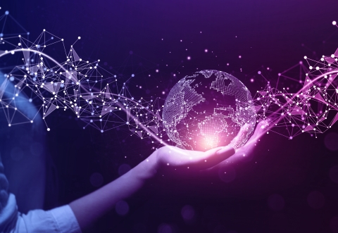 Hand holding a crystal ball of the world in purple and dark blue hues